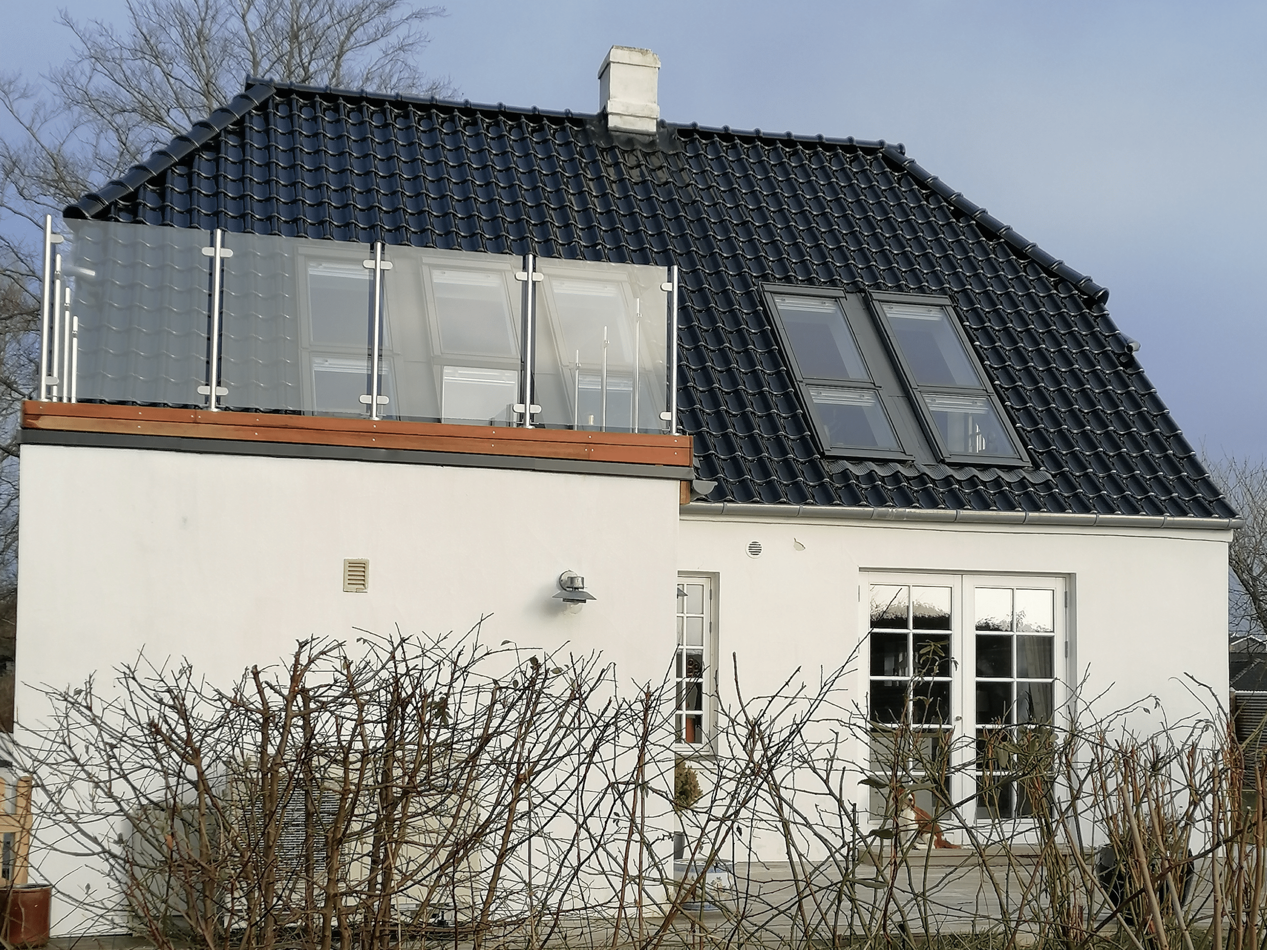Vitt hus med glasräcke på balkong inför försäljning
