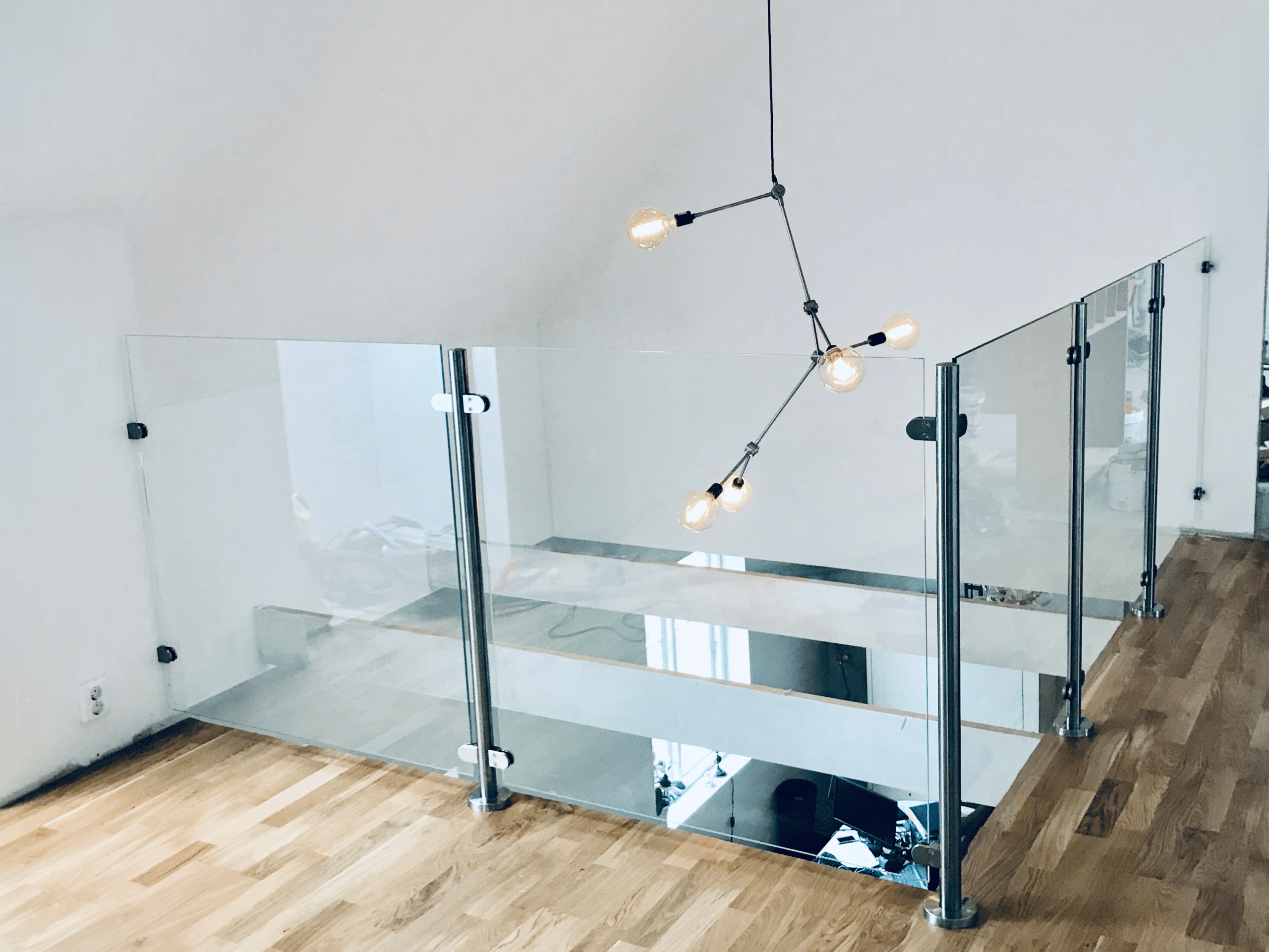 Glasräcke vid loft och trappöppning som släpper igenom ljus mellan våningsplanen.