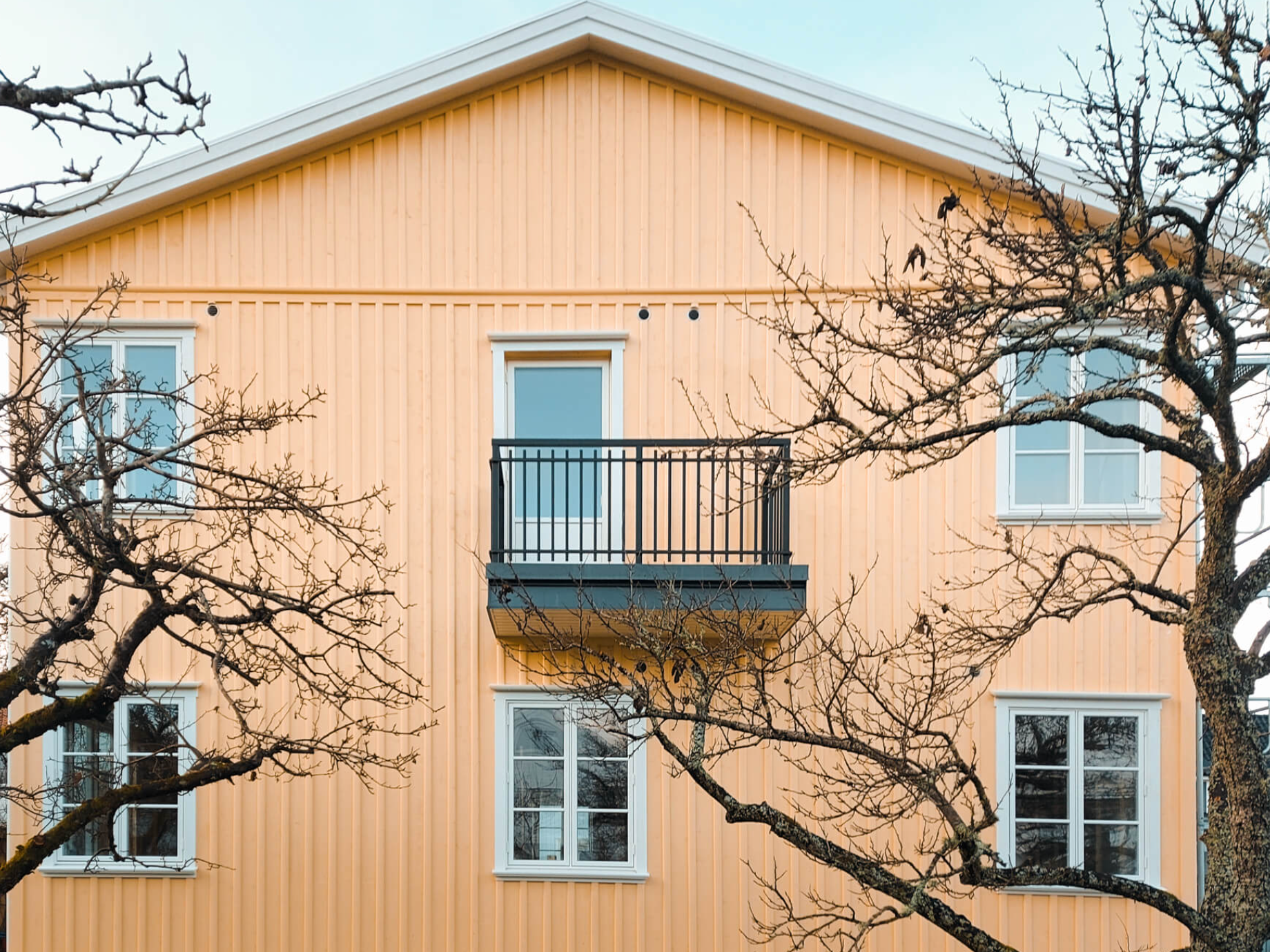 Svart räcke i smidesstil på liten balkong vid gul träfasad – ett rostskyddat alternativ till armeringsjärn som räcke.