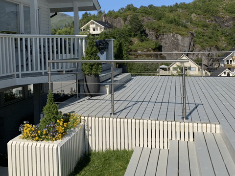 Altan med trappa och vajerräcke vid vit villa
