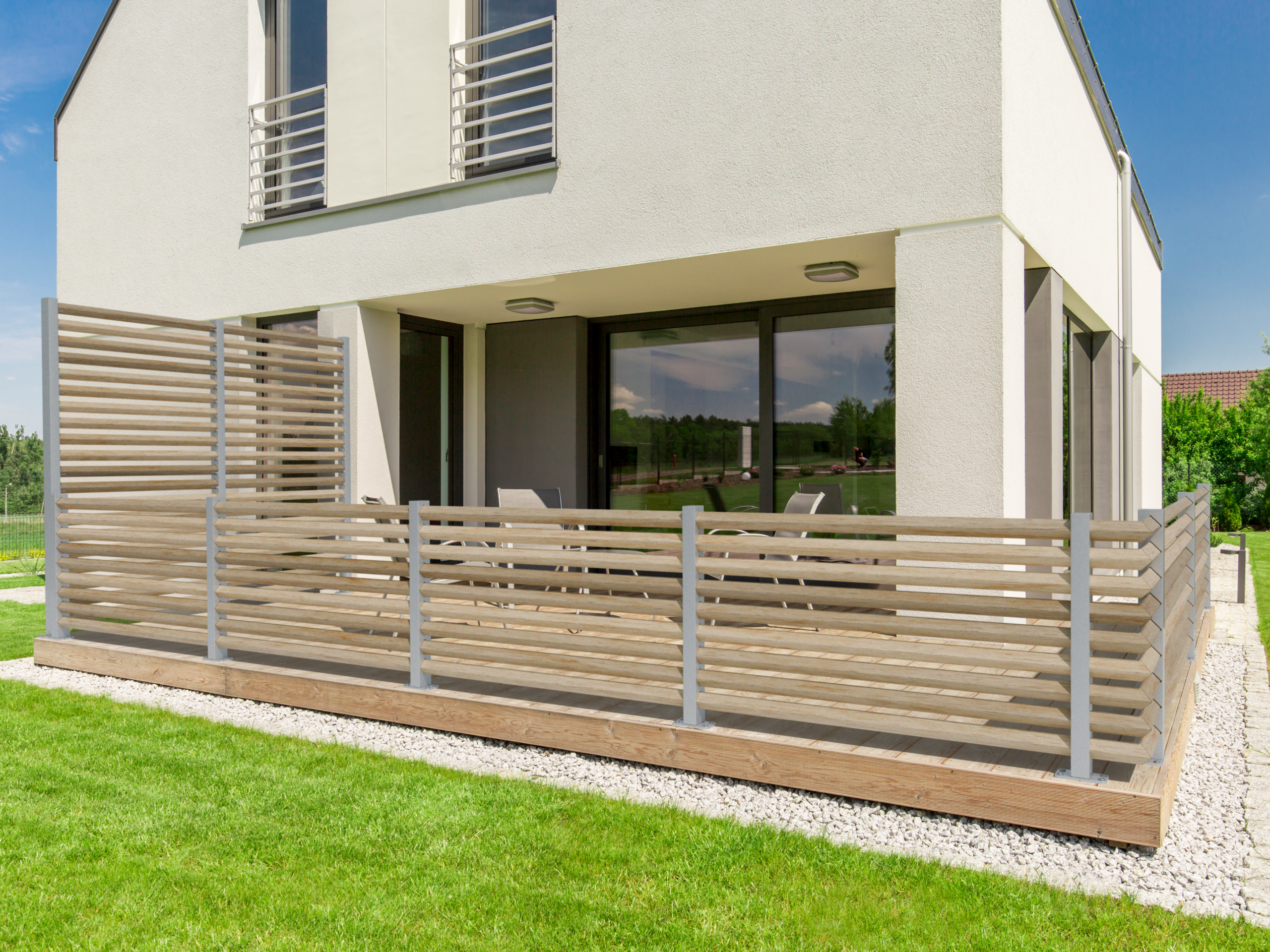 Avskärmning i träribbor längs altan vid modern villa med grönska.