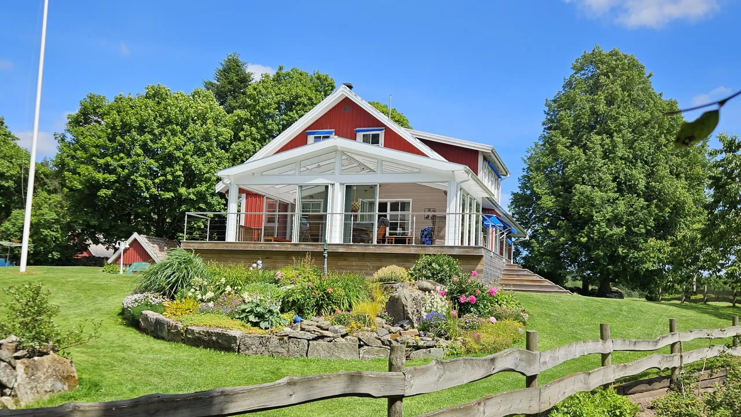 Villa med veranda och glasräcke vid entré och trädgård