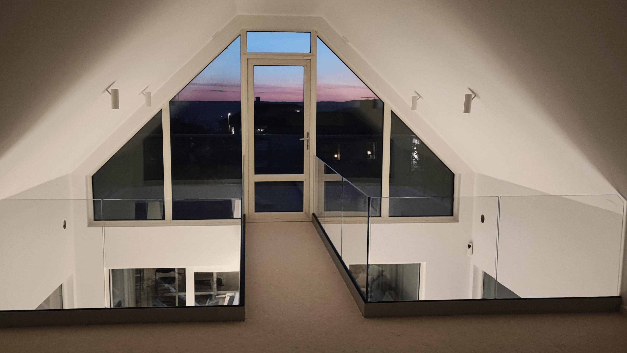 Glasräcke inomhus vid loft i öppen planlösning med ljus och rymd.